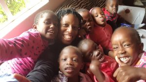 Kennesha holding camera, children looking camera and smiling