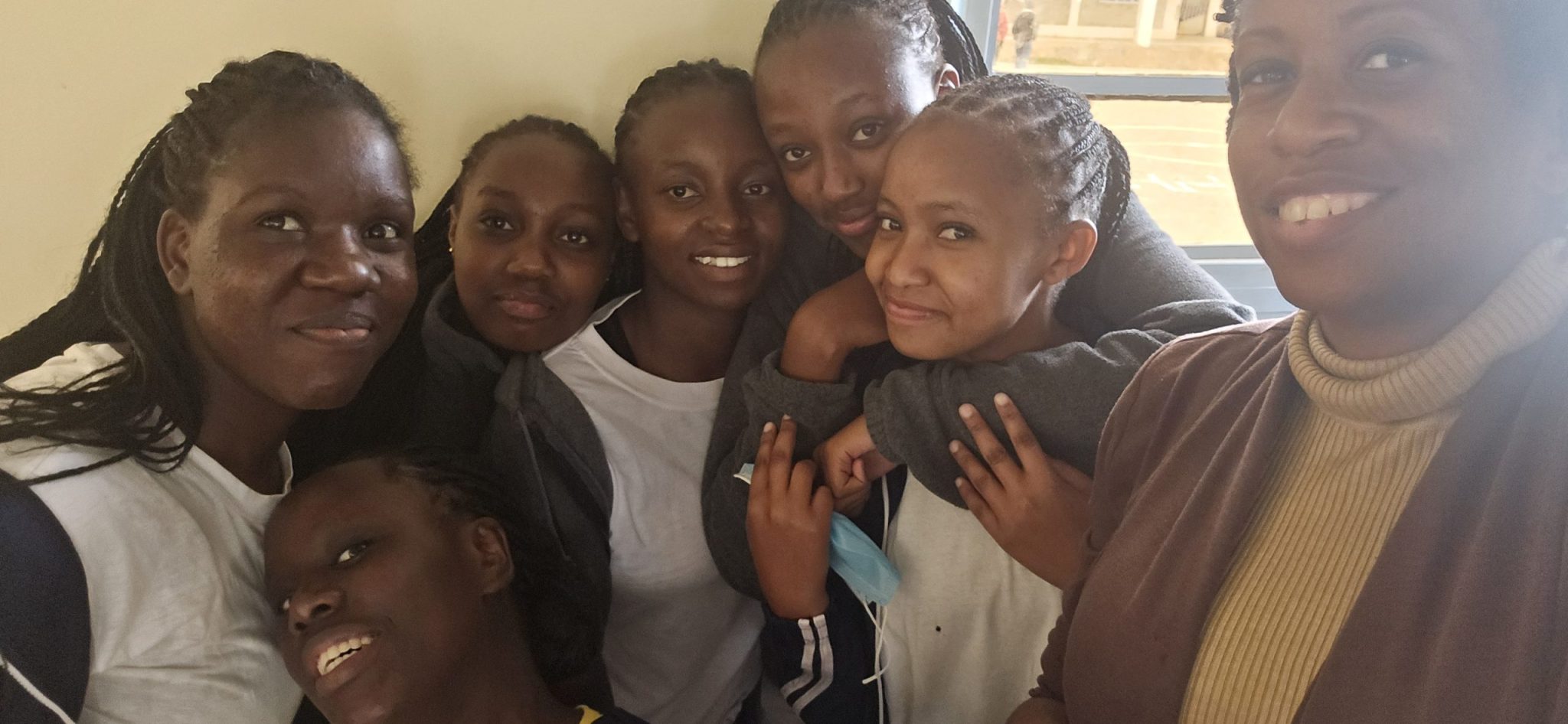 Group of students and an adult posing closely together for a selfie at Faith Premier High School.