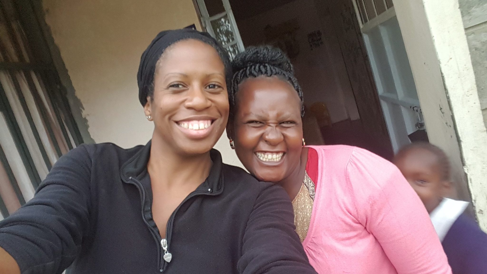Kennesha and Mom Tere smiling together outside a doorway at Happy Life in Juja Farm, Kenya, in 2018.