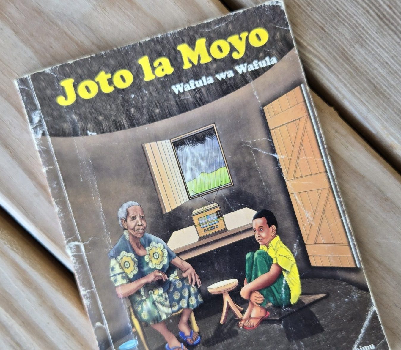 Worn copy of Joto la Moyo by Wafula wa Wafula resting on a wooden table.