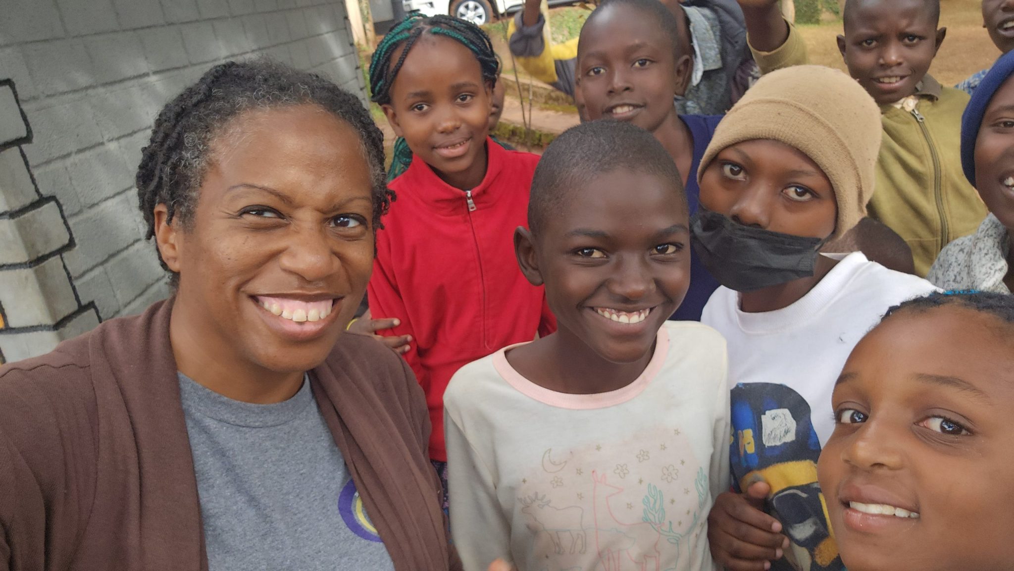 Kennesha smiling for a selfie with a group of children at orphanage compound during a mission visit in Kisii, Kenya.