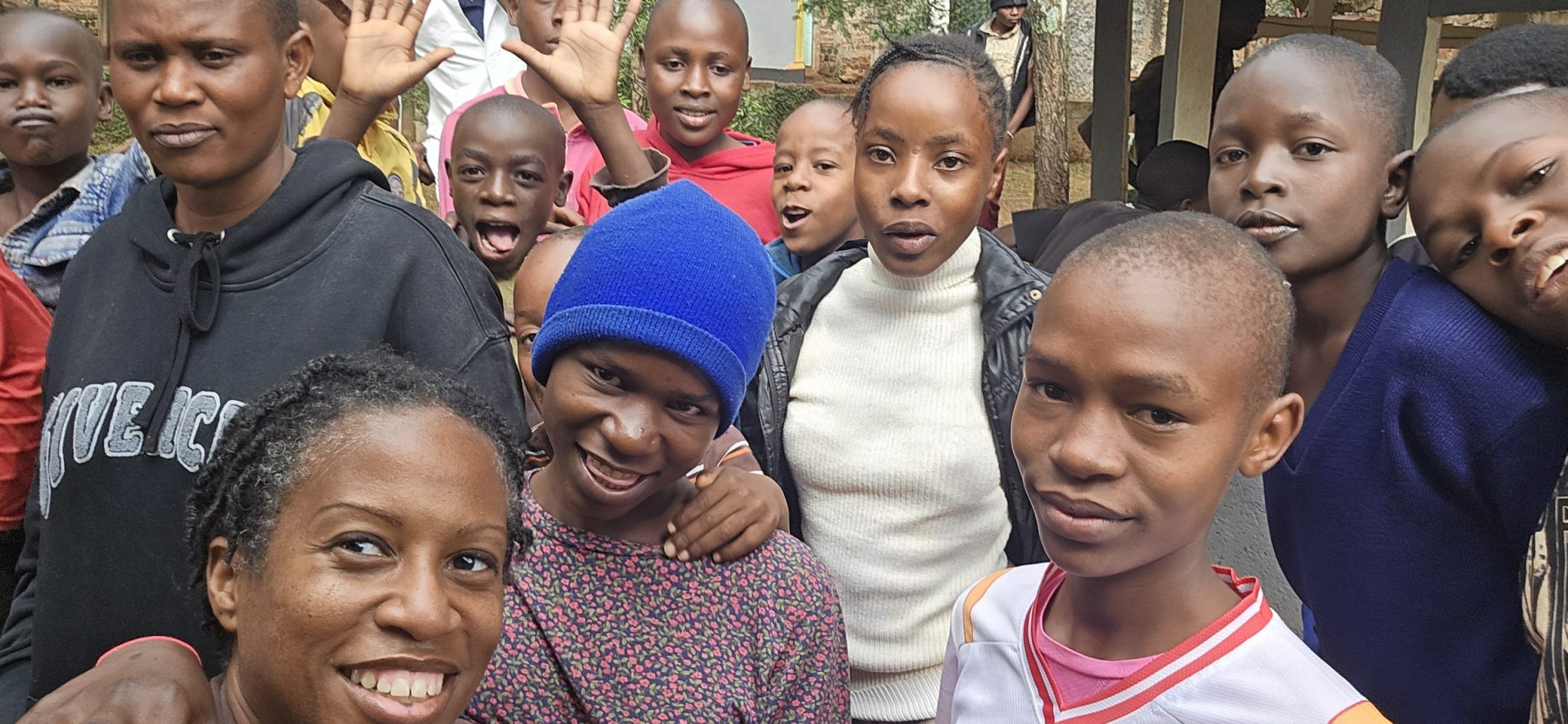Kennesha taking a group selfie with children and adults gathered outdoors in Kisii, Kenya.
